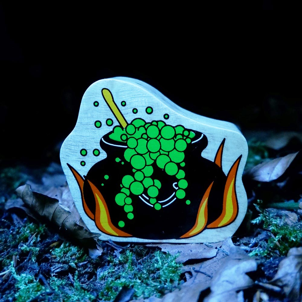 Close up of the Lanka Kade eco-friendly wooden cauldron toy in the dark on some autumn leaves