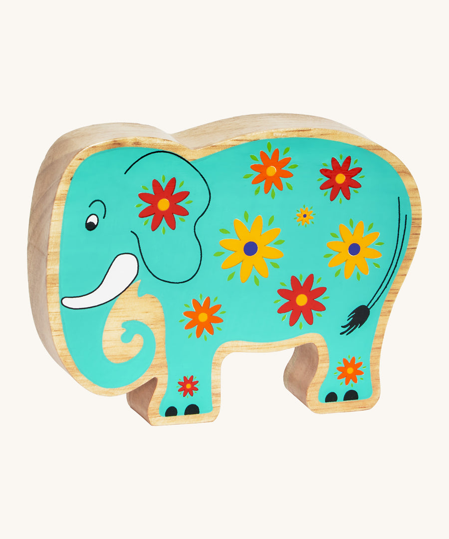 A green wooden Lanka Kade elephant with yellow and red flowers on a cream background.