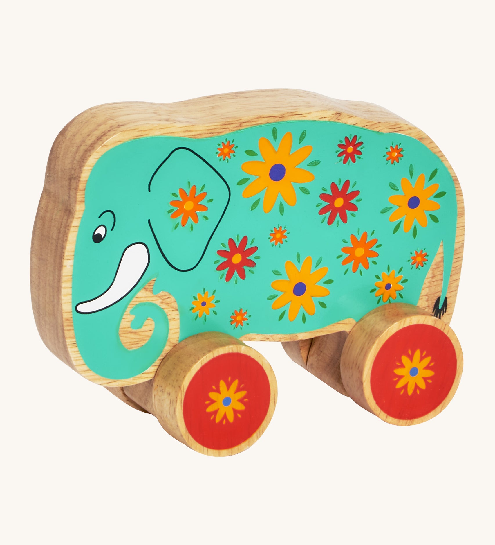 A green wooden Lanka Kade push along elephant with yellow and red flowers with red wheels on a cream background.