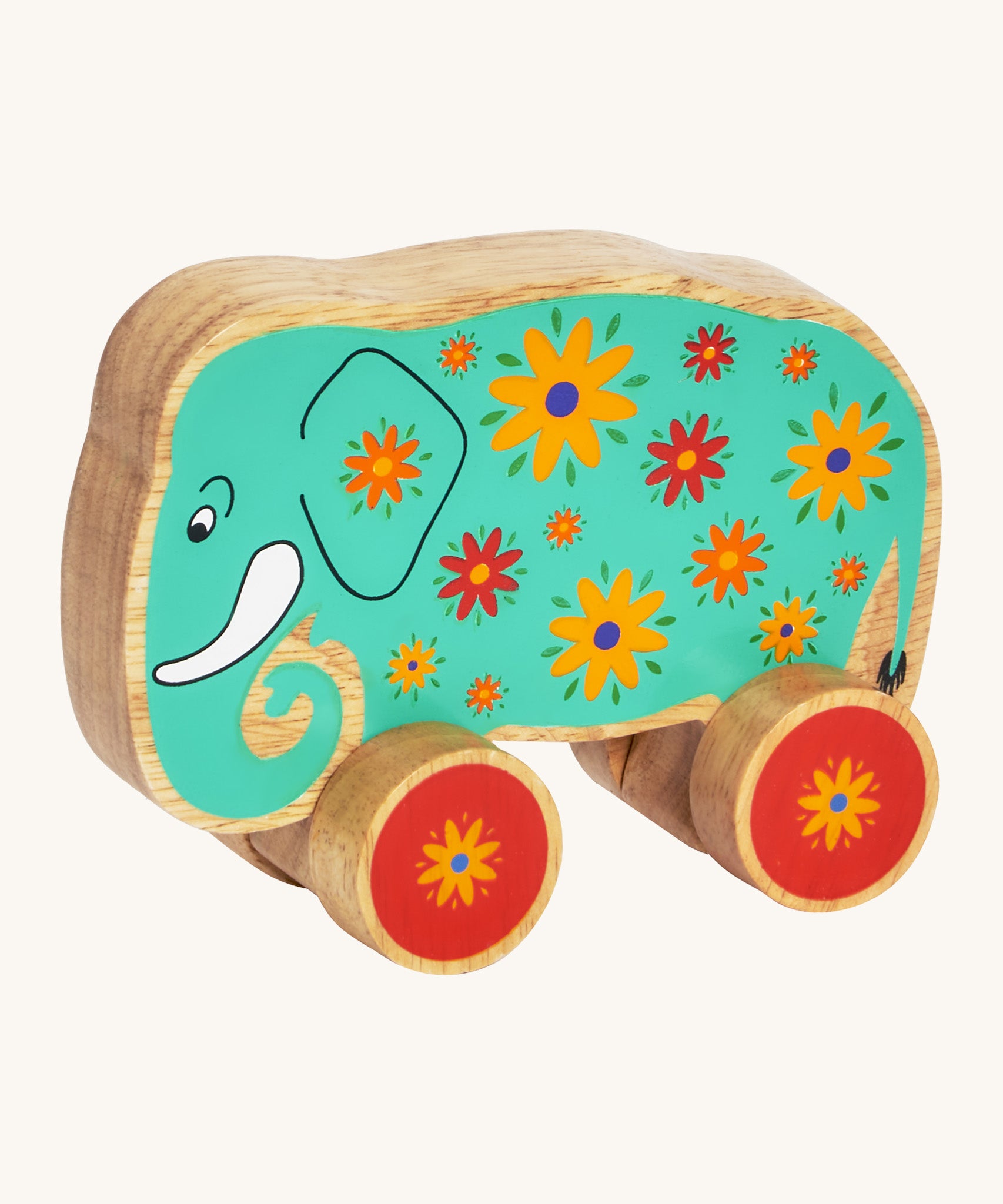 A green wooden Lanka Kade push along elephant with yellow and red flowers with red wheels on a cream background.