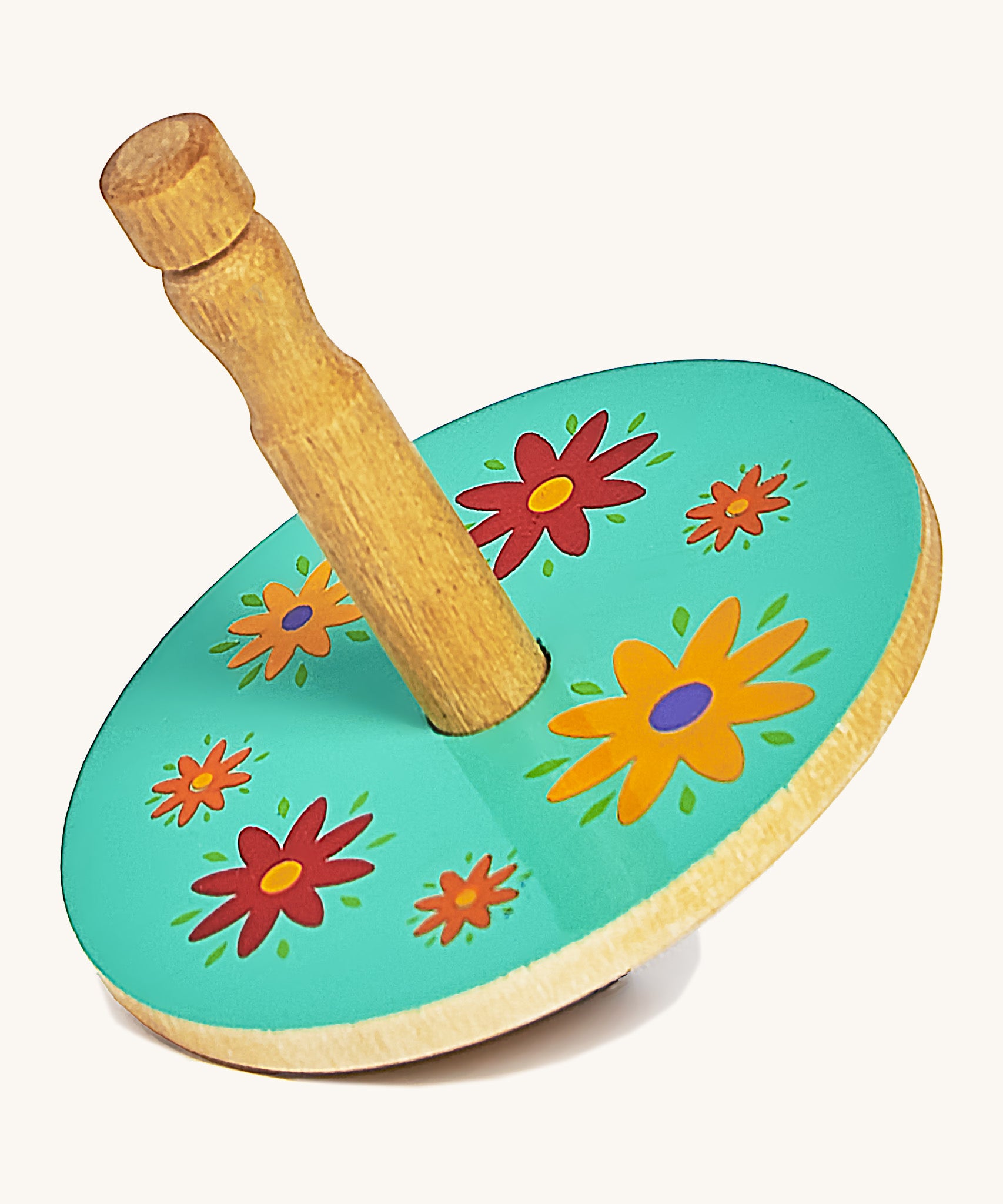 A green wooden Lanka Kade spinning top with red and yellow flowers on a cream background.