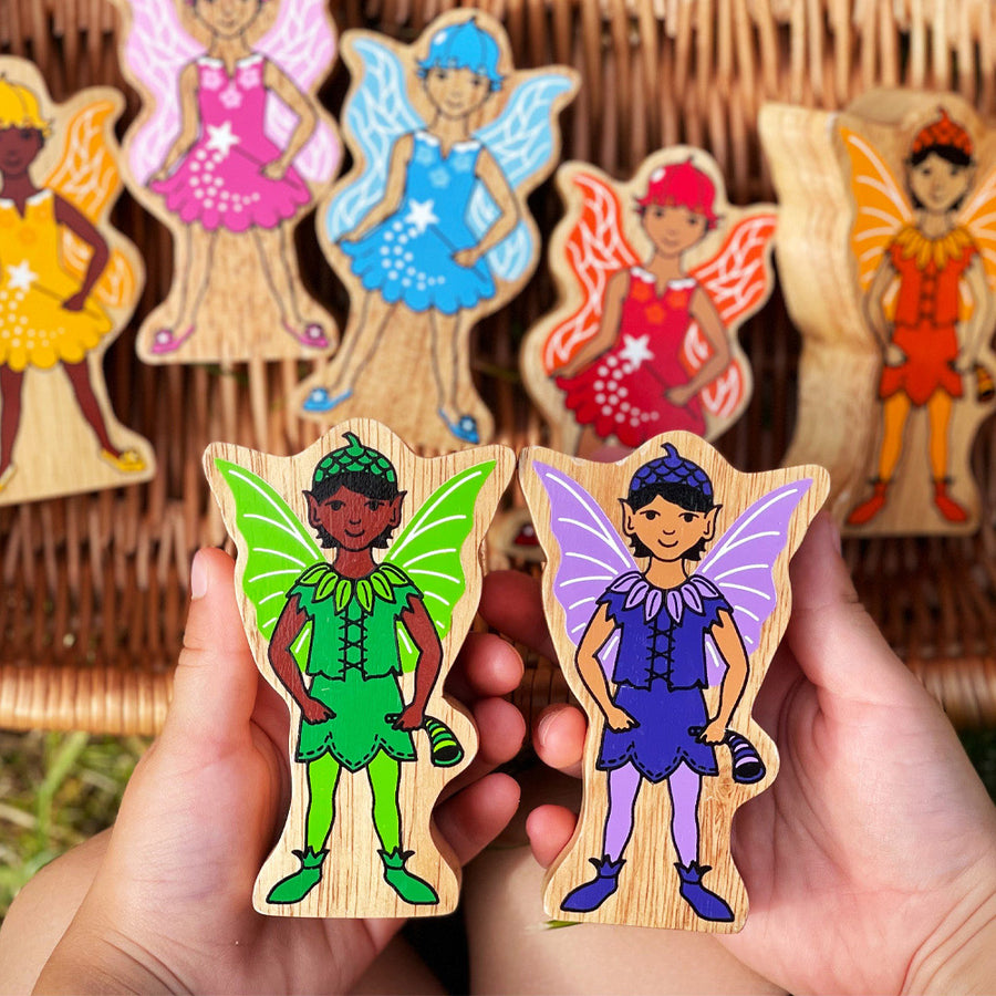 Close up of a childs hands holding some Lanka Kade Waldorf rainbow fairy figures above a wicker basket