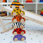 Lanka Kade wooden animal printed cars stacked on a playmat next to a Triclimb wooden slide and wooden climbing frame. Features a bumblebee, leopard, tiger, zebra, ladybird and beetle printed wooden car.