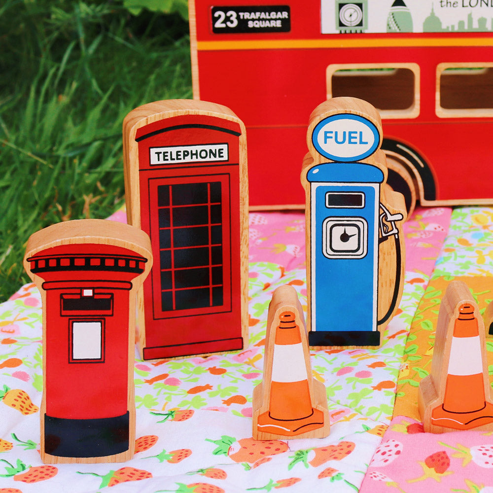 Close up of the Lanka Kade handmade wooden toy town accessories on a colourful blanket next to a toy bus