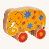 A yellow wooden Lanka Kade push along elephant with blue and red flowers with red wheels on a cream background.