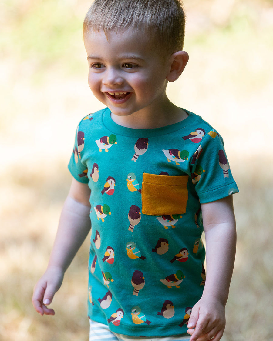 A child playing in a grassy field wearing the Little Green Radicals Garden Birds Organic T-Shirt & Jogger Playset