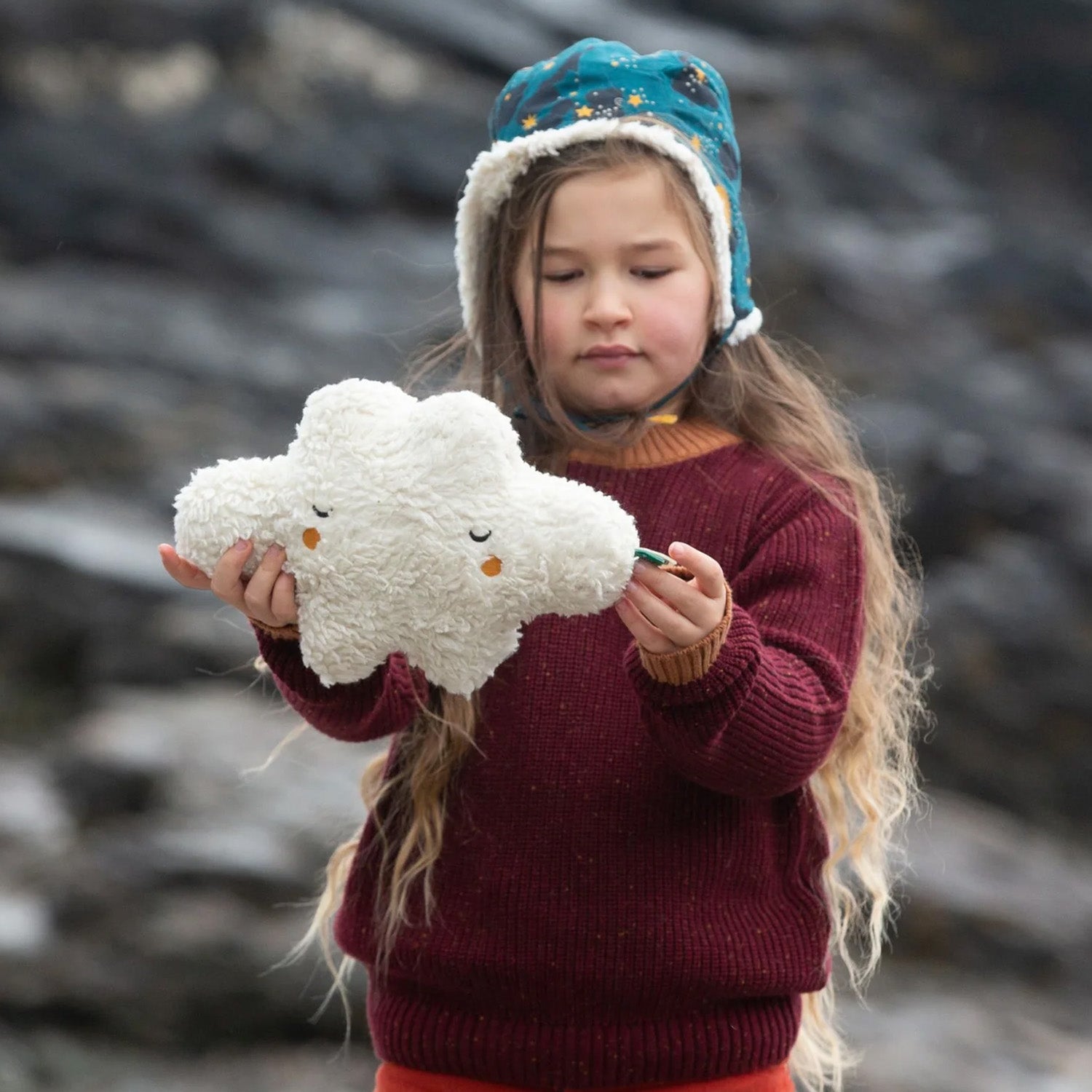 A child plays with the LGR Fluffy Cloud Organic Cotton Soft Toy in an outdoor setting.