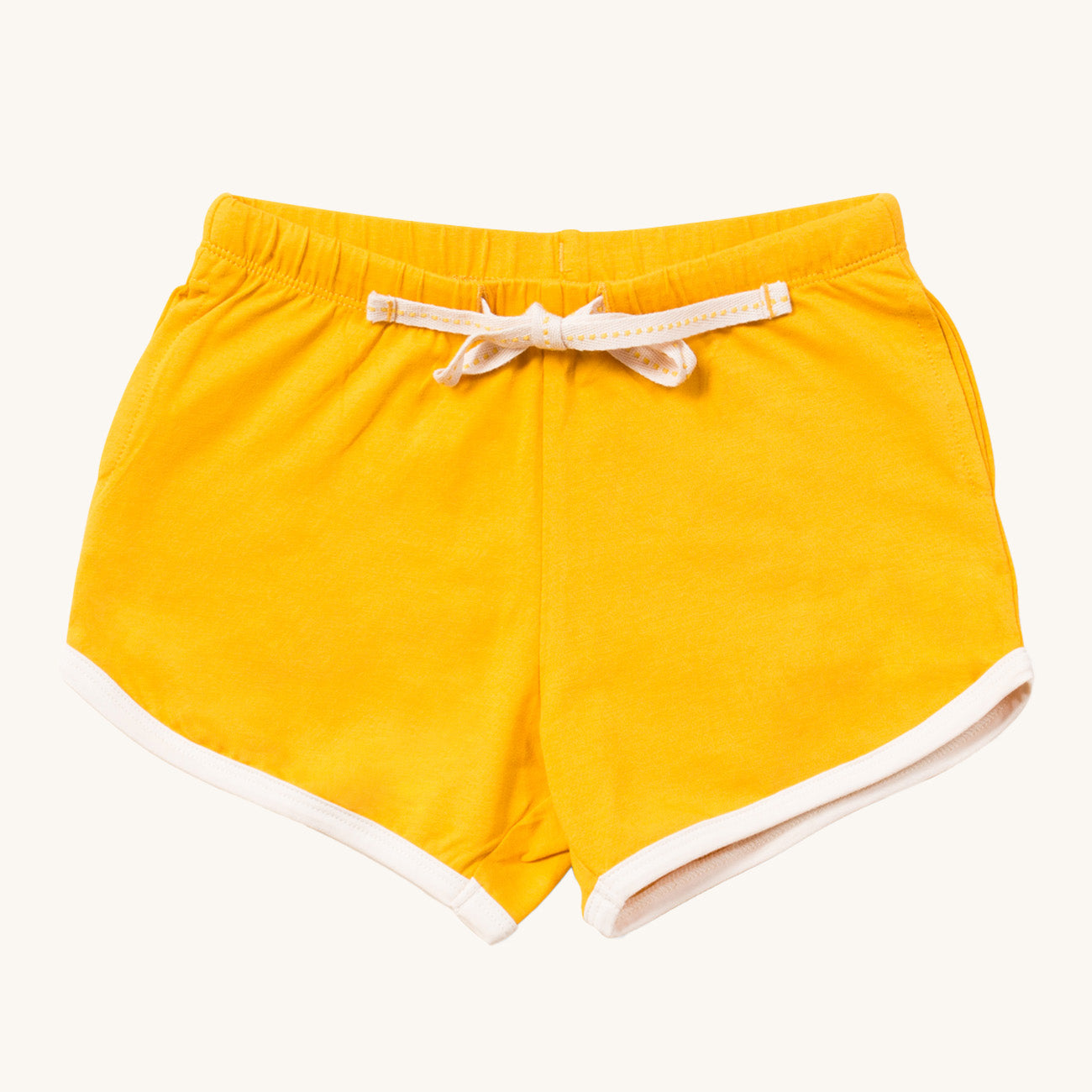 Gold Run Around Shorts. Made from GOTS Organic Cotton, these shorts are a rich gold colour, with off white piping on the legs, drawstring and side pockets for treasures