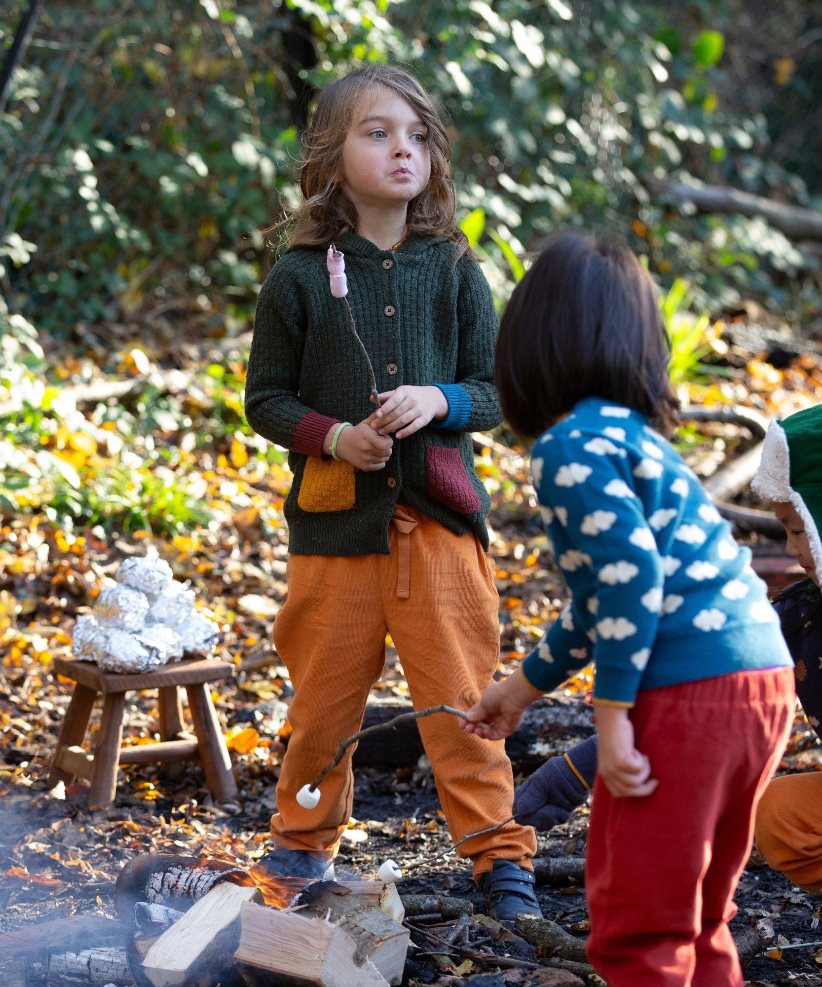 Little Green Radicals kids fern green knitted hooded cardigan with yellow and red pockets worn by a child