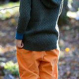 Little Green Radicals kids fern green knitted hooded cardigan with yellow and red pockets worn by a child hem detail