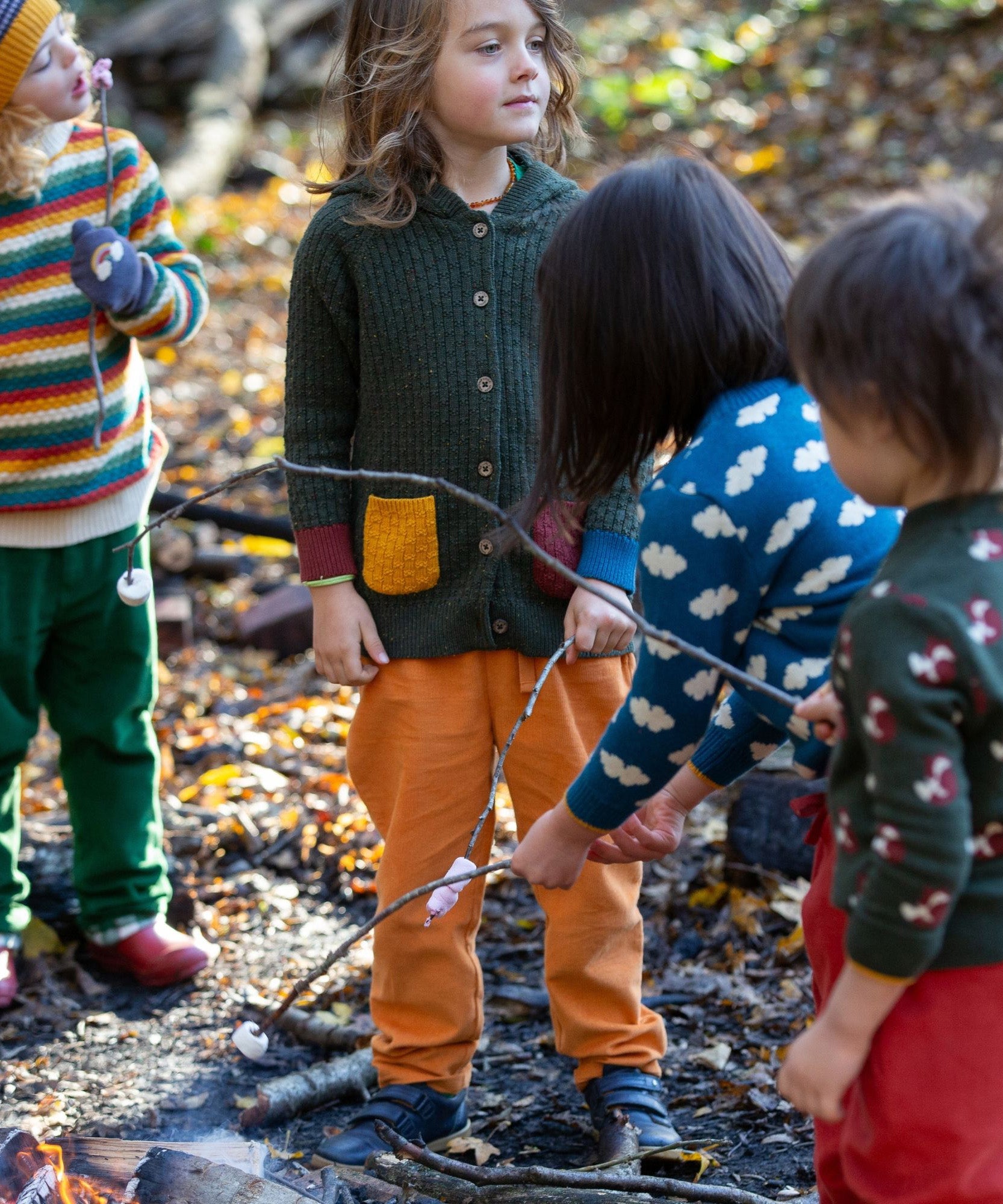 Little Green Radicals kids fern green knitted hooded cardigan with yellow and red pockets worn by a child