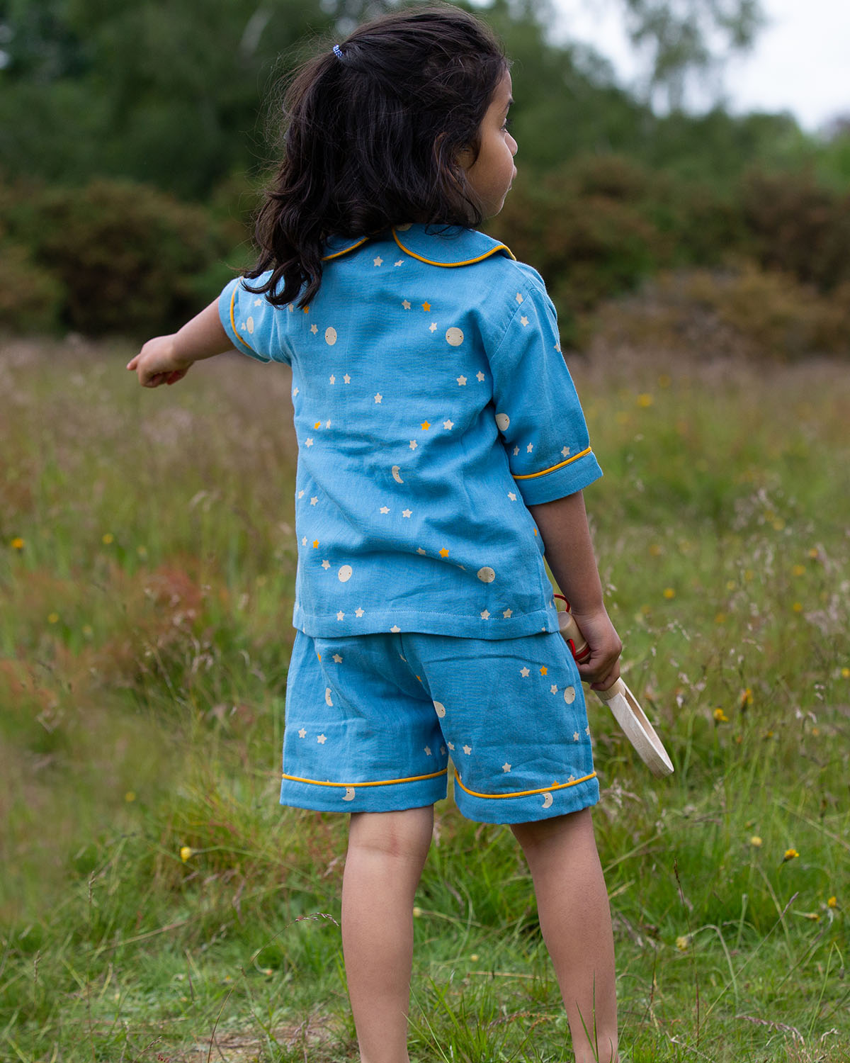 Children playing together in front of a tent. The child in the middle is wearing the Little Green Radicals Organic Cotton Dusk Button Through Pyjama Short Set. Made from GOTS organic Cotton