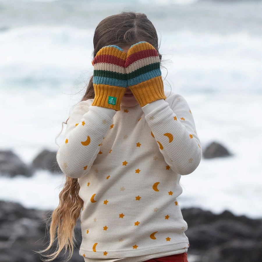 A child plays outdoors wearing the LGR Rainbow Striped Knitted Mittens.