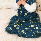 Close up of child sat on a spotty bed wearing the little green radicals organic cotton moon and stars sleeping bag