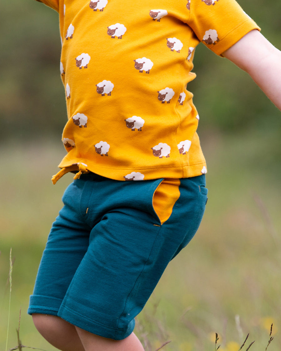 A child happily playing outside wearing the Little Green Radicals Counting Sheep Short Sleeve T-Shirt. Made from GOTS organic cotton