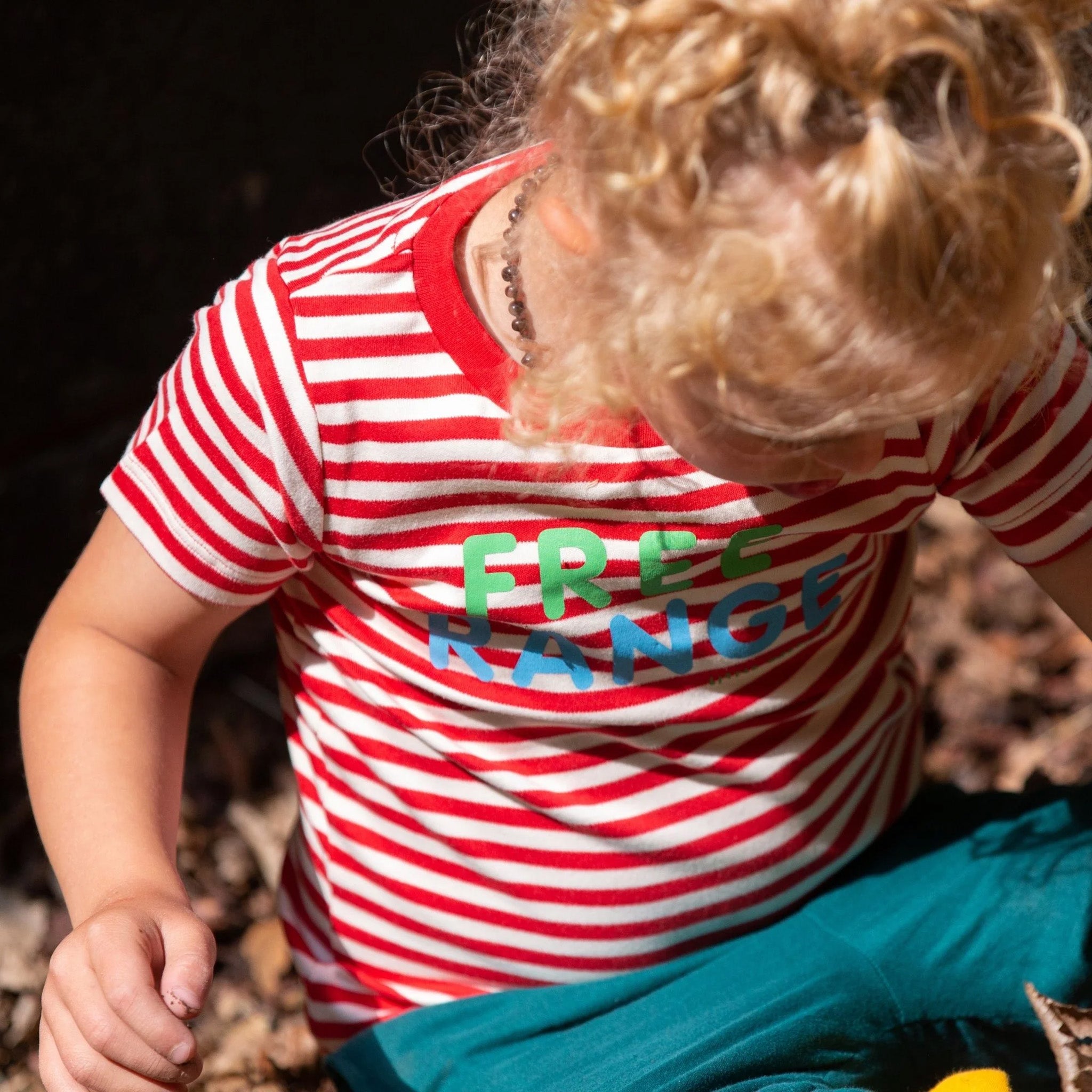 A child stood outside wearing the Little Green Radicals Free Range Top