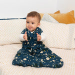 Child sat on a spotty bed wearing the LGR eco-friendly soft sleeping bag 