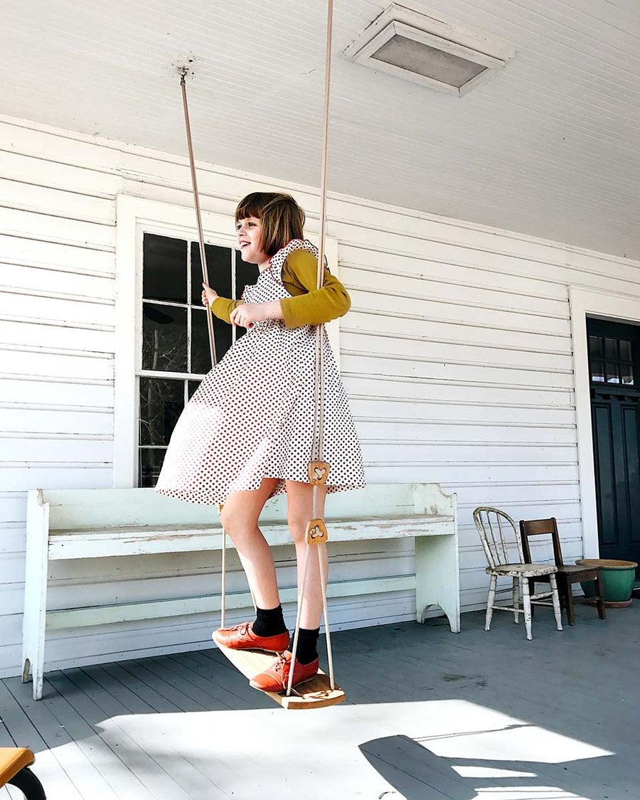 Girl stood on the Lillagunga oak wood grand swing on a wooden porch