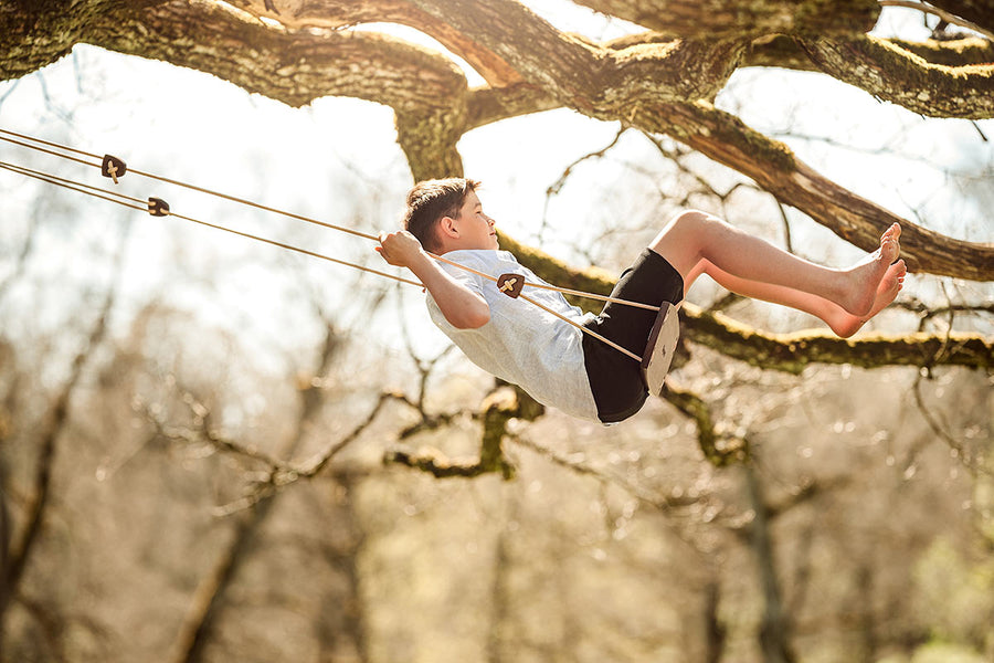 Boy sat swinging on a Lillagunga grand swing in the branches of a big tree