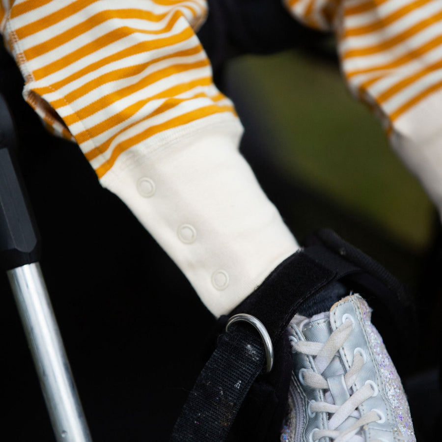 Child wearing the Little Green Radicals Adaptive Extra Long Joggers in gold showing a close up of the popper closures on the leg cuffs