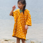 A child wearing the Little Green Radicals Children's Bees patteren Hooded organic cotton Beach Towel Poncho