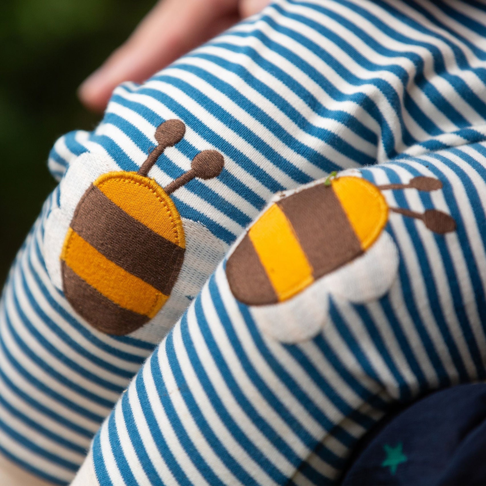 A close up of a child's knees wearing the Little Green Radicals Bees Knees Patch Striped blue and white Joggers