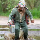 A child wearing the green coloured Little Green Radicals trousers with a from one to another knitted cardigan.