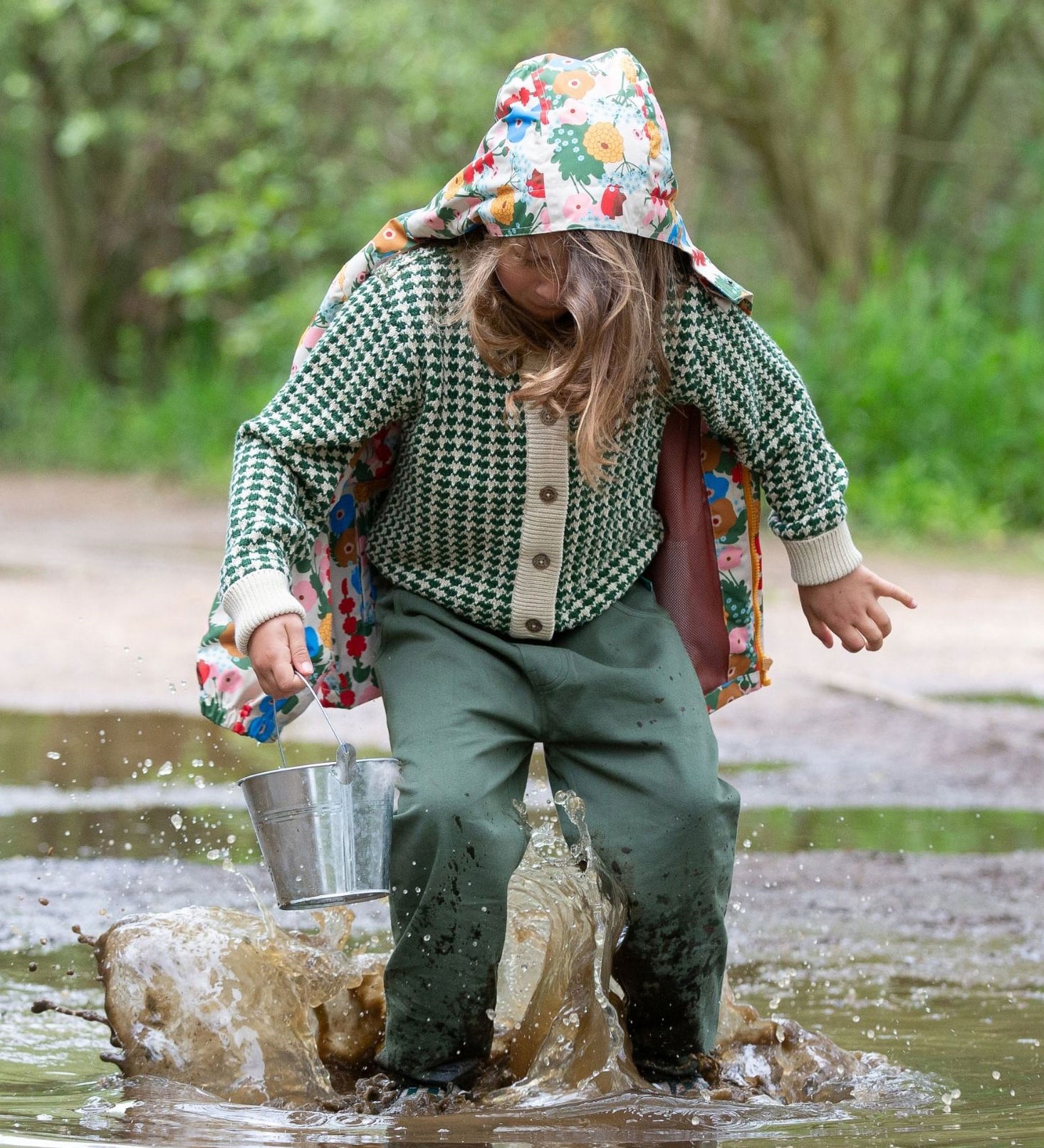 A child wearing the green coloured Little Green Radicals trousers with a from one to another knitted cardigan.