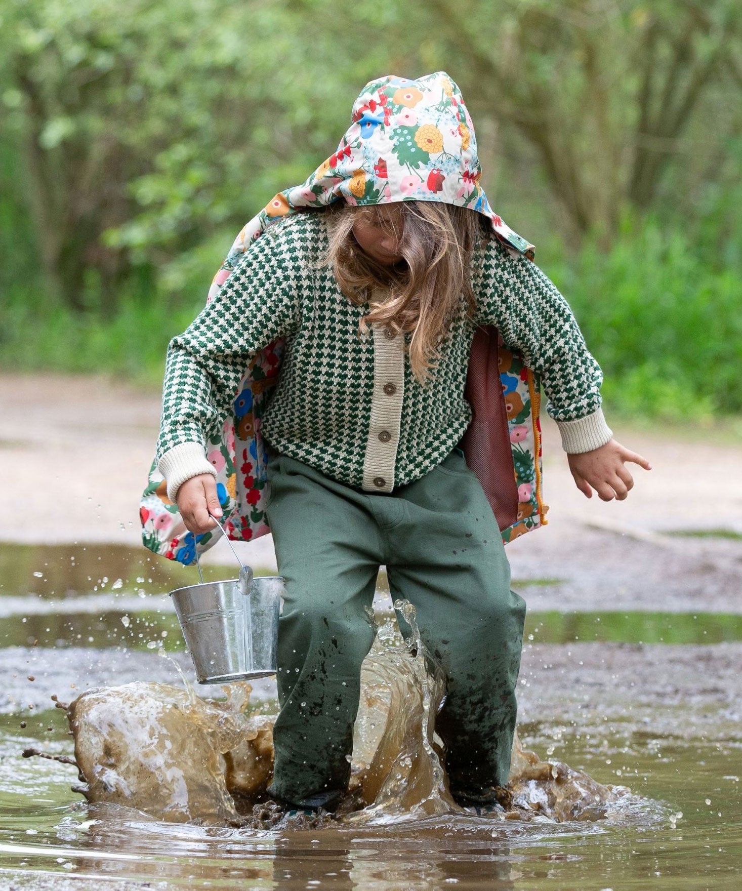 A child wearing the green coloured Little Green Radicals trousers with a from one to another knitted cardigan.