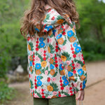 Little Green Radicals Child's Flora & Fauna vintage style flower print Waterproof Raincoat. The child is facing away from the camera showing a view of the back of the jacket.