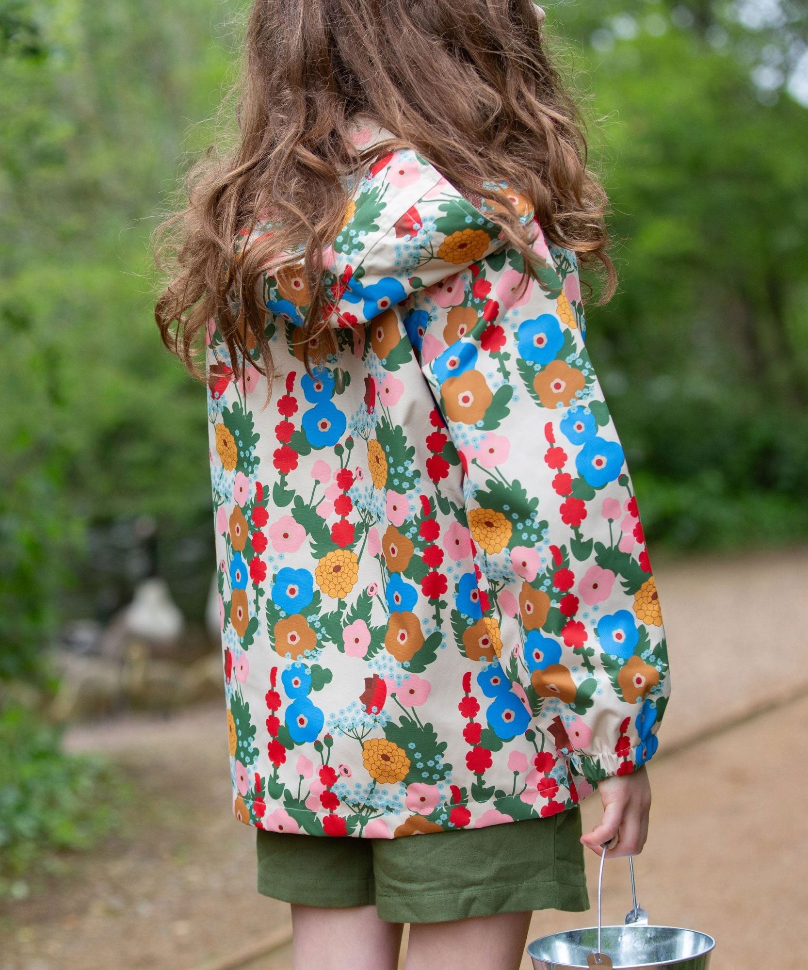 Little Green Radicals Child's Flora & Fauna vintage style flower print Waterproof Raincoat. The child is facing away from the camera showing a view of the back of the jacket.