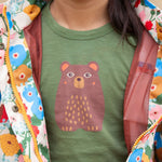 A close up of a child wearing the Little Green Radicals Kids Organic Cotton Green Bear Short Sleeve T-short.