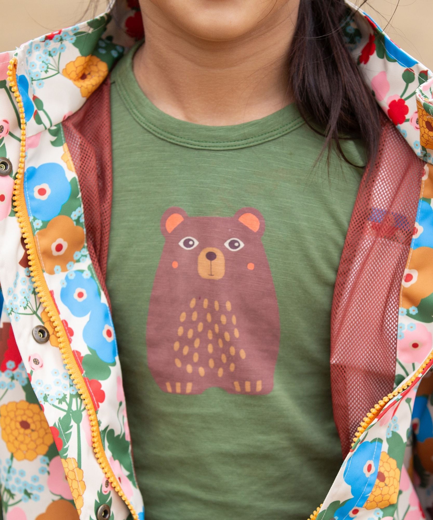 A close up of a child wearing the Little Green Radicals Kids Organic Cotton Green Bear Short Sleeve T-short.