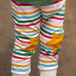 A close up of a child's legs wearing the Little Green Radicals Stars Knee Patch Rainbow Striped Children's Organic Cotton Joggers