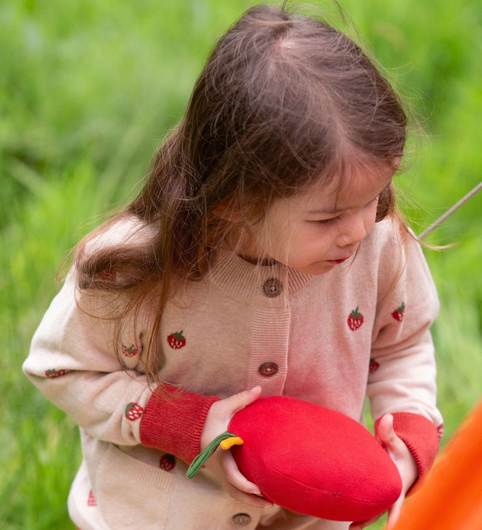 A child wearing the Little Green Radicals organic From One To Another Strawberry Days print child's Knitted Cardigan