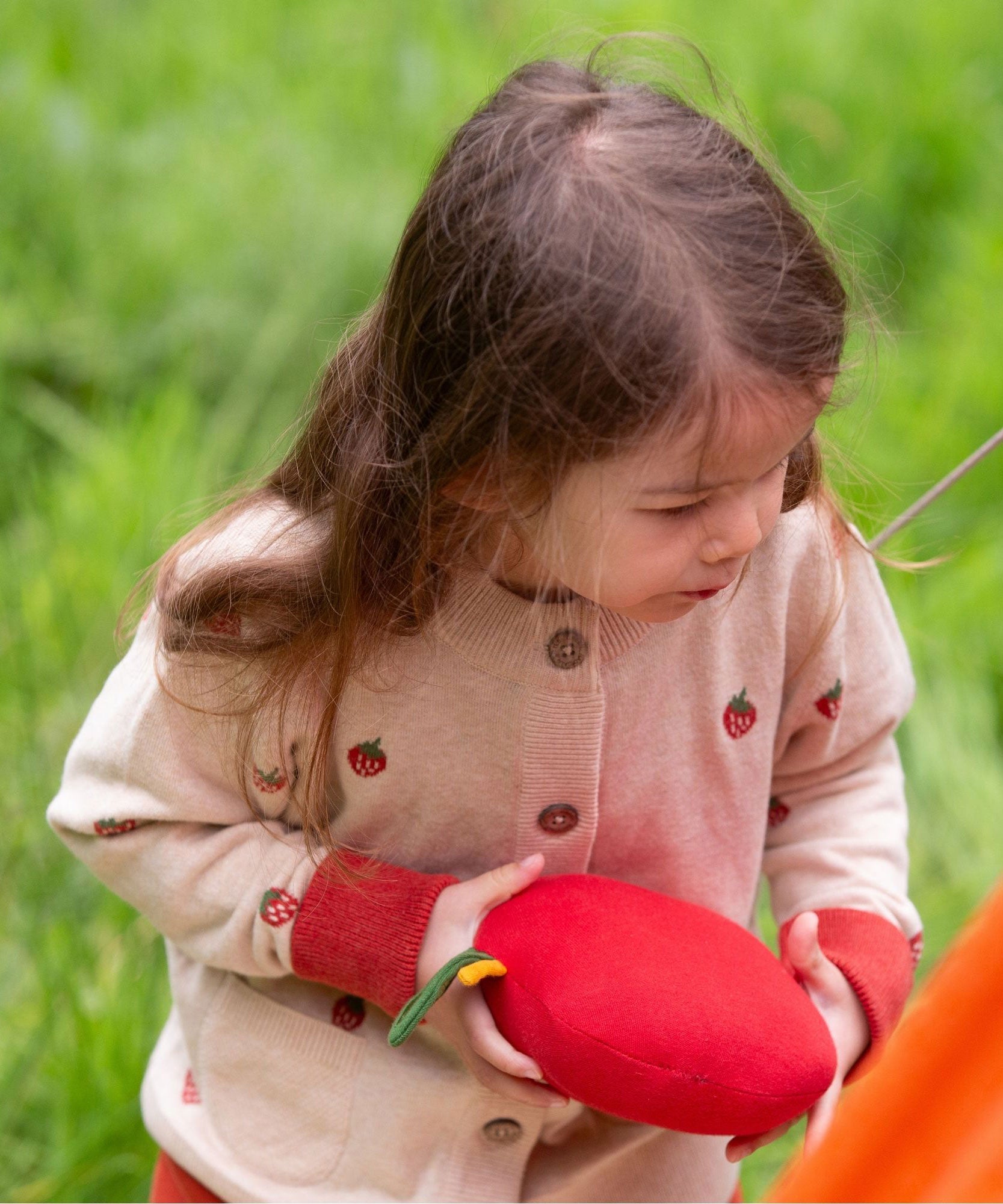 A child wearing the Little Green Radicals organic From One To Another Strawberry Days print child's Knitted Cardigan