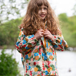 A child wearing the Little Green Radicals Child's Flora & Fauna vintage style flower print Waterproof Raincoat