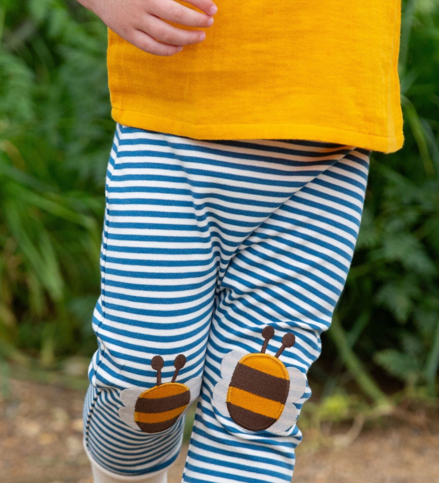 A close up of a child's legs wearing the Little Green Radicals Bees Knees Patch Striped blue and white Joggers