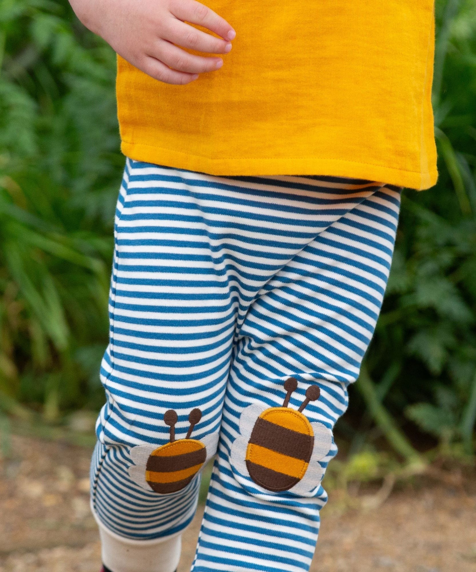 A close up of a child's legs wearing the Little Green Radicals Bees Knees Patch Striped blue and white Joggers