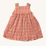 Little Green Radicals Child's Organic Cotton Strawberry Days Reversible Pinny Dress shown with the red gingham side on the outside.