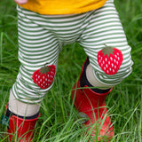 A close up of a child's legs wearing the Little Green Radicals Strawberry Knee Patch Green and Cream Striped Organic Cotton Joggers.