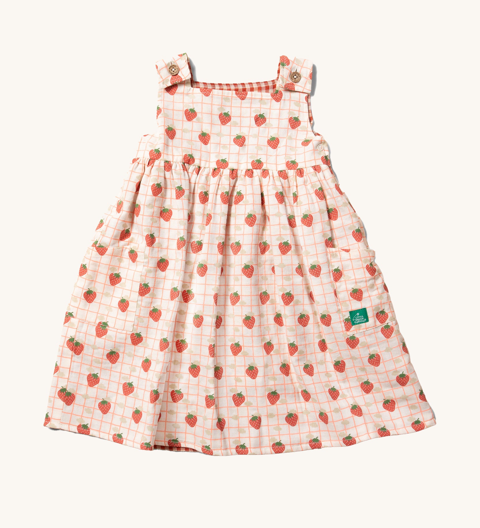 Little Green Radicals Child's Organic Cotton Strawberry Days Reversible Pinny Dress shown with the strawberry print on the outside.