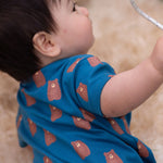 A close up of a child wearing the Little Green Radicals Teddy Bears Organic Cotton Shortie Romper. 