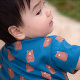 A close up of a child wearing the Little Green Radicals Teddy Bears Organic Cotton Shortie Romper. 