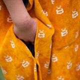 A close up of a child wearing the Little Green Radicals Children's Bees pattern Hooded organic cotton Beach Towel Poncho, the photo focuses on the side