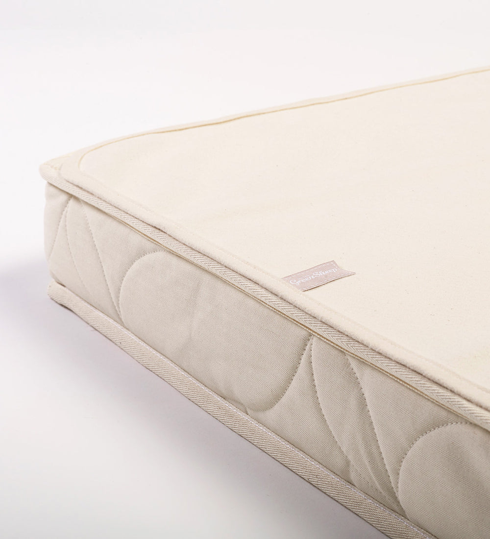 A close up of a Little Green Sheep Organic Cot Mattress Protector placed on a matress