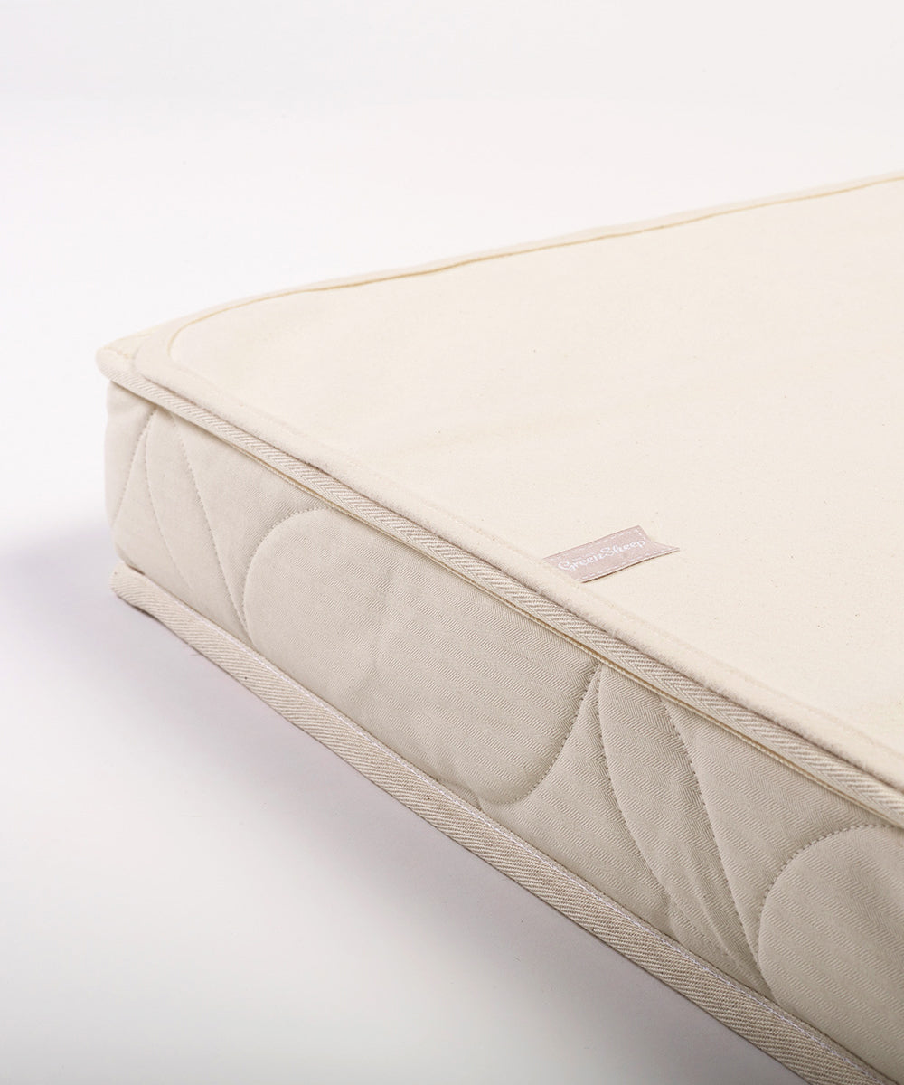 A close up of a Little Green Sheep Organic Junior Mattress Protector placed on a mattress 