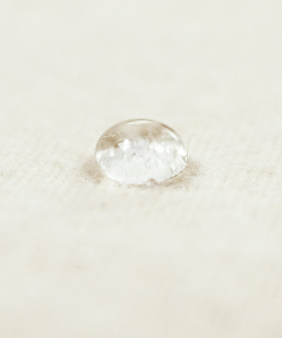 A close up of a water droplet on the Little Green Sheep Organic Moses Basket / Pram Mattress Protector