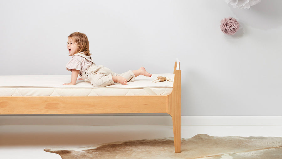 A toddler lying on a Little Green Sheep organic wool mattress