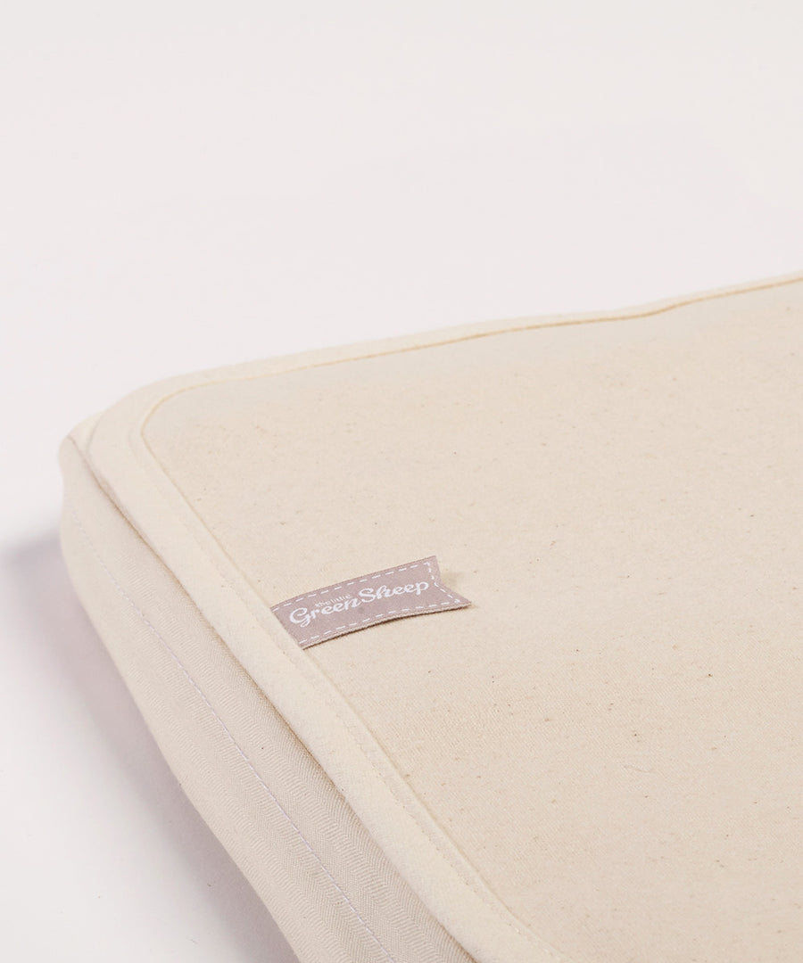 A close up of the corner of a Little Green Sheep Organic Crib Mattress Protector placed on a mattress